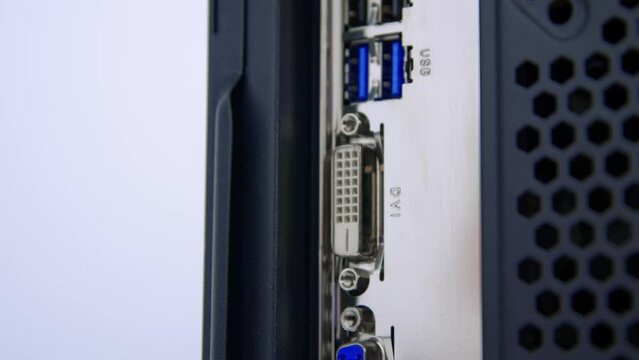 Caucasian male hand pushes a moulded plug into the DVI monitor socket on a desktop PC motherboard.