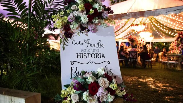 Cada familia tiene una historia, bienvenidos, letrero en madera blanco con mensaje de bienvenida para bodas decorado con flores y con se&ntilde;as de gotas de lluvia 60fps