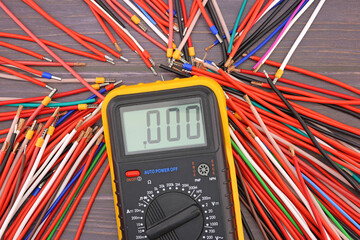 Digital multimeter and insulated copper mounting wires. Close-up. Soft focus.