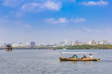 Traditional wooden boat in front of the skyline of Hangzhou, China