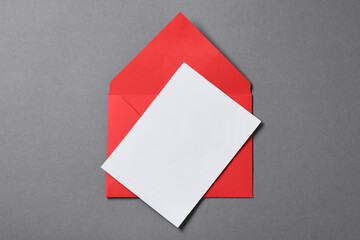 Blank sheet of paper and letter envelope on grey background, top view