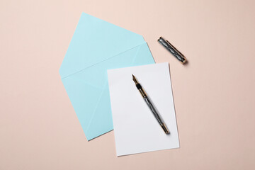 Blank sheet of paper, letter envelope and pen on beige background, top view