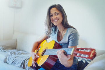 Woman, guitar and smile on sofa for portrait with music, creativity and relax in home living room....