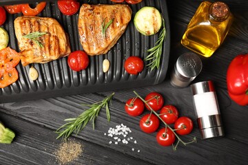Flat lay composition with electric grill and different products on black wooden table