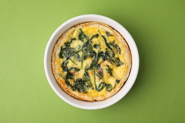 Delicious pie with spinach on green background, top view