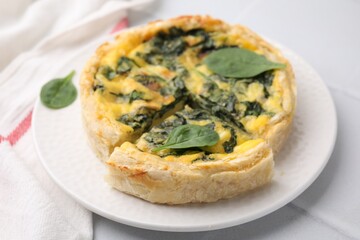 Delicious pie with spinach on white tiled table, closeup