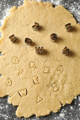 Making shortcrust pastry. Raw dough and cookie cutters on grey table, top view