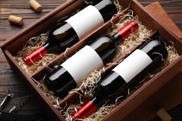 Box with wine bottles on wooden table, above view