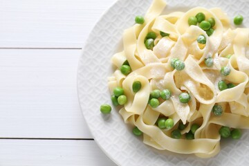 Delicious pasta with green peas on white wooden table, top view. Space for text