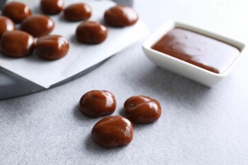 Tasty candies, caramel sauce and salt on light grey table