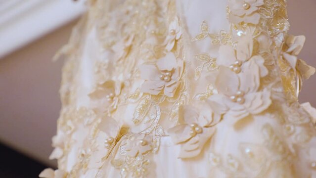 Beige wedding gown hangs on a wooden hanger from the celling close Up 60fps