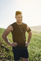 Fototapeta premium Man, earphones and confident running portrait in outdoor, marathon training and health in countryside. Male person, streaming and song for workout in nature, fitness and proud of cardio or music