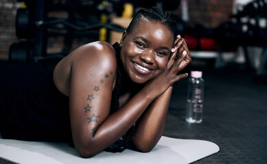 Black woman, portrait and floor for fitness, gym and confidence for sports workout. Smile, bodybuilder or cardio training for body health and wellness, active or exercise for African person in studio