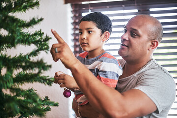 Dad, Christmas and kid with decoration on tree for festive season, December tradition and...