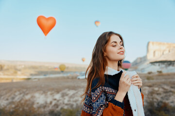 Woman standing in front of heartshaped balloon with dreamy background sky