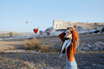 Woman enjoying hot air balloons flying over picturesque field on a sunny day