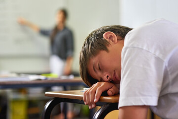 Education, student and boy sleeping on desk, tired and bored in classroom, burnout and fatigue in...