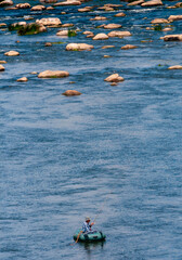 a fisherman in a rubber boat catches fish in the middle of the Southern Bug river, Ukraine