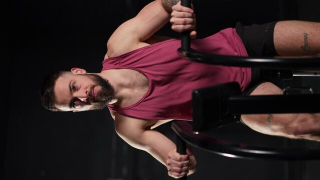 Man exercising on elliptical cross-trainer machine, wearing activewear. Routine workout for physical and mental health. Vertical view.