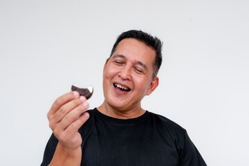 A middle aged man enjoys a nice snack - an extra rich cream filled cookie.