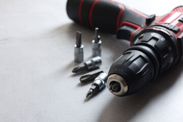 Modern electric screwdriver and bits on grey table, closeup. Space for text