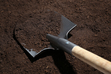 Metal shovel on fertile soil. Gardening tool