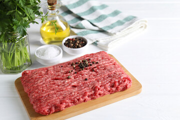 Raw ground meat, spices, oil and parsley on white wooden table
