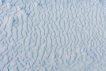 Weathered ice and frozen snow in the form of needle crystals on the bank of the Tiligul Estuary on a sunny day