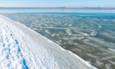 Ice floating near the shore in the form of oblong ice floes, rolled around by waves and a storm in the Tiligul estuary