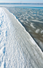 Ice floating near the shore in the form of oblong ice floes, rolled around by waves and a storm in...