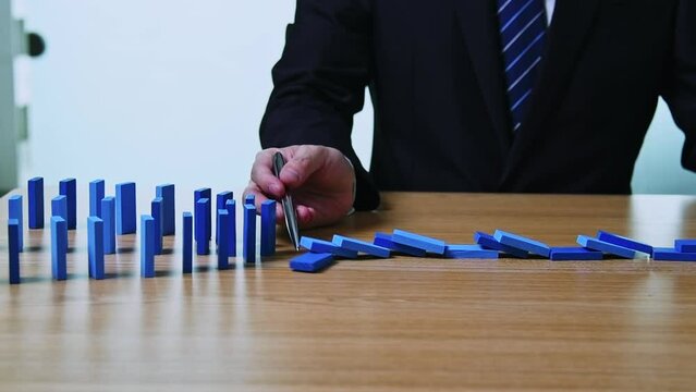 Slow motion video of businessman hand  holding a pen stop domino blocks