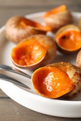 Delicious cooked snails with fork on table, closeup