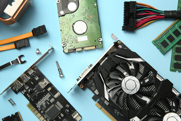 Graphics card and other computer hardware on light blue background, flat lay