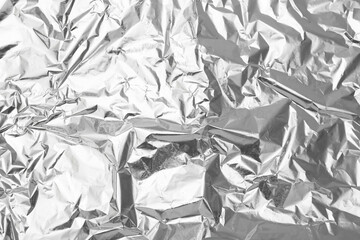 Crumpled silver foil as background, top view