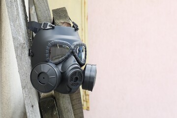 One gas mask hanging on building outdoors. Space for text