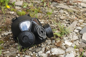 One gas mask on ground with stones outdoors. Space for text