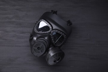 One gas mask on black wooden background, top view