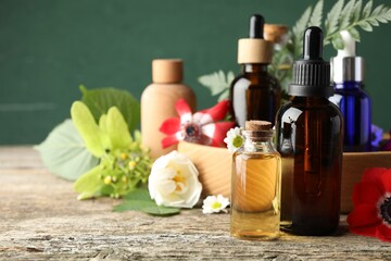 Aromatherapy. Different essential oils, flowers and green leaves on wooden table