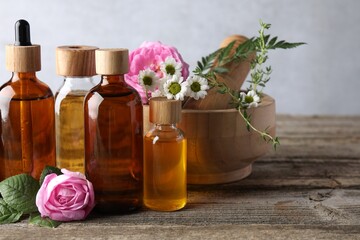 Aromatherapy. Different essential oils, flowers, mortar and pestle on wooden table