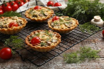 Tasty tartlets with cheese, tomatoes, mushrooms and dill on wooden rustic table, closeup