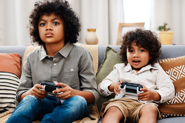 Couch, video games and children in living room for technology, controllers and entertainment in...
