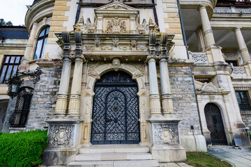 Obraz premium Door at the entry to the beautiful neo-Renaissance building of Peles Castle (Castelul Peles) near Bucegi Mountains (Muntii Bucegi) in a cloudy summer day in Sinaia town, Romania .