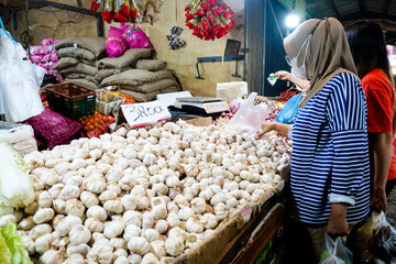 Consumers buy garlic at the traditional market in Pontianak City, Indonesia. Pile of garlic on a basket, displayed in traditional market stall.