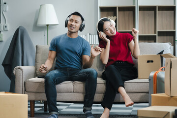 Young couple relaxing sitting on the sofa using the computer laptop around cardboard boxes, very...