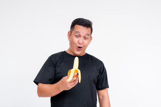 A middle aged Asian man looks amazed at a peeled lakatan banana