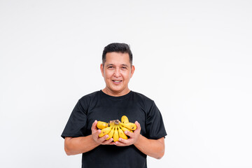 Middle aged Asian man smiling while holding a bunch of bananas, isolated on white