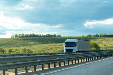 Front view of truck with cargo trailer driving on highway transporting goods at summer day. Cargo...