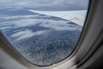 Gaze out of an airplane window to witness the harmonious blend of the airplane wing against the backdrop of the city and sky.