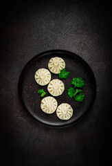 Khinkali, a traditional Georgian dish, with spices and herbs, on a black plate, top view, no people,
