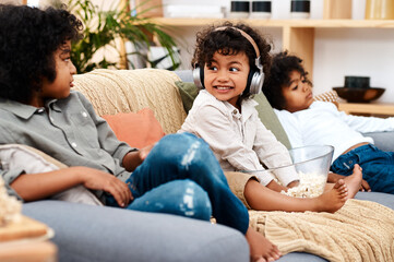 Headphones, child and family on couch for streaming, music and ebook for education or listening on couch. Boy, brothers and online for movies, streaming and relax on sofa with popcorn in home